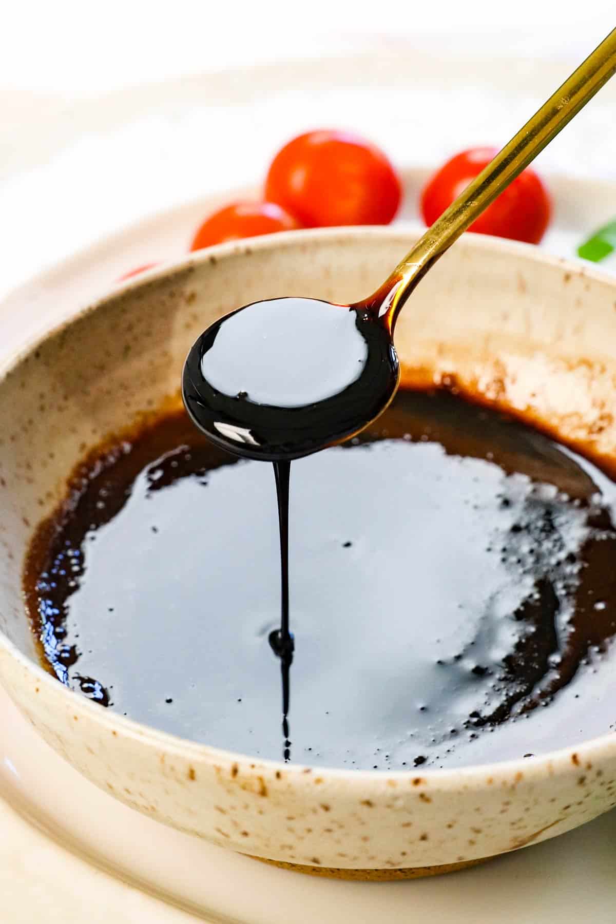 a spoon of balsamic vinegar glaze drizzling the glaze showing the consistency