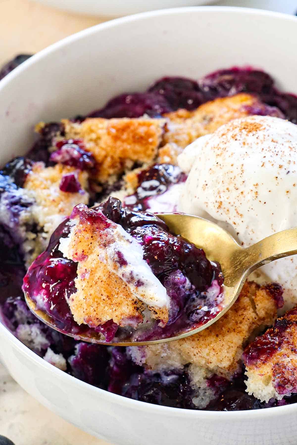 scooping up a bite of easy blueberry cobbler recipe showing the juicy berries and golden, fluffy biscuit topping