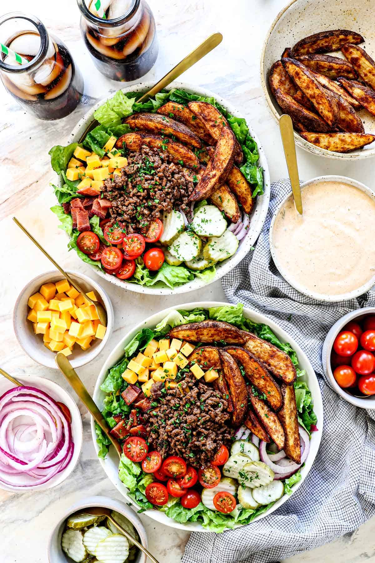 top view of burger bowl recipe in bowls being served with toppings and soda