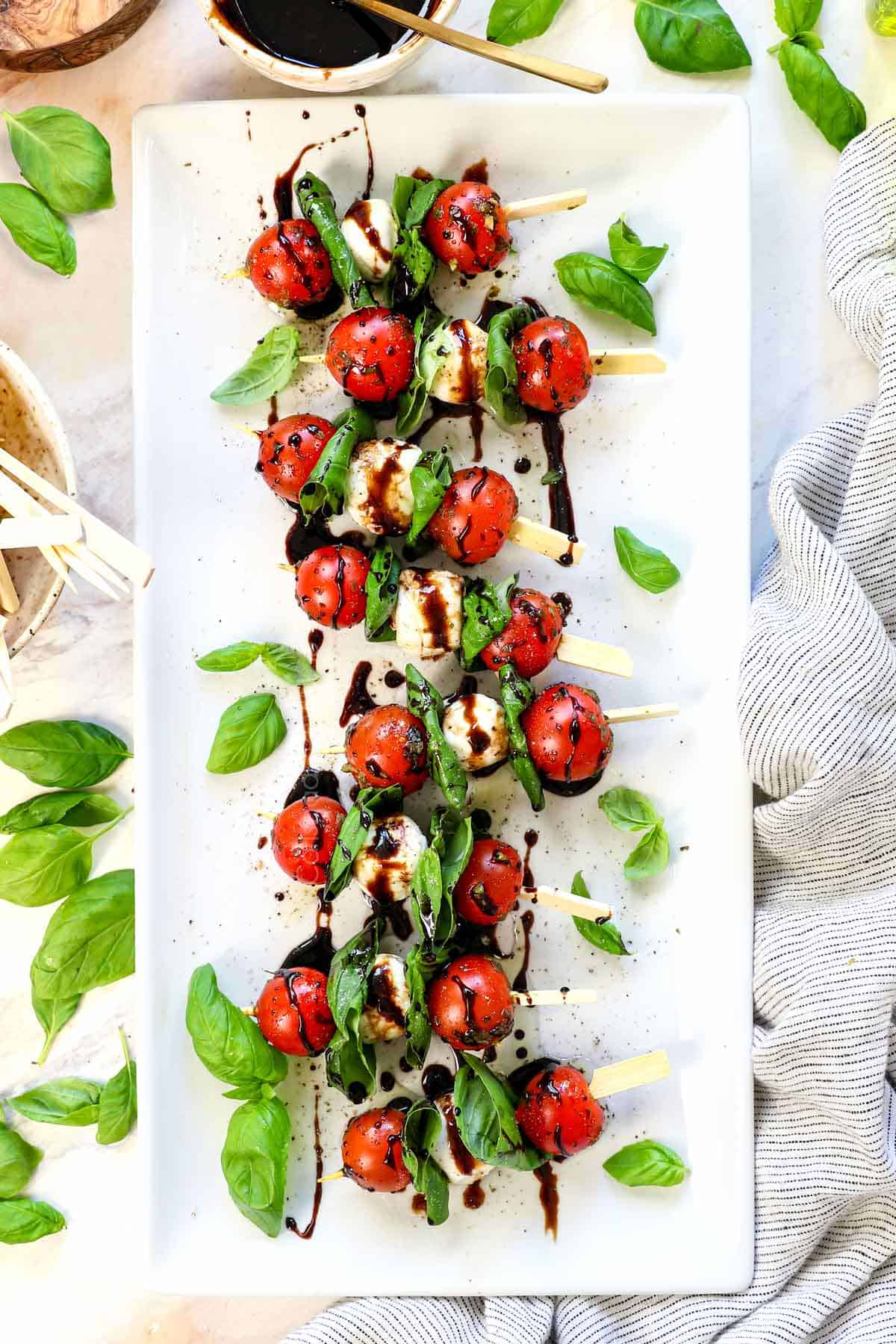 showing how to make Caprese skewers by sprinkling with salt and pepper
