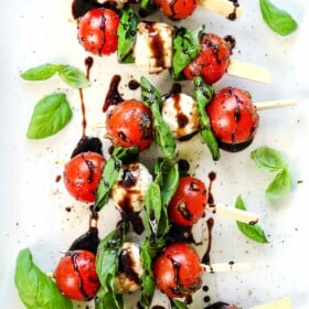 top view of Caprese skewers being served on a platter drizzled with balsamic glaze and olive oil