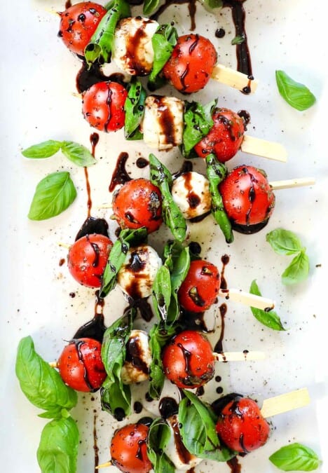 top view of Caprese skewers being served on a platter drizzled with balsamic glaze and olive oil