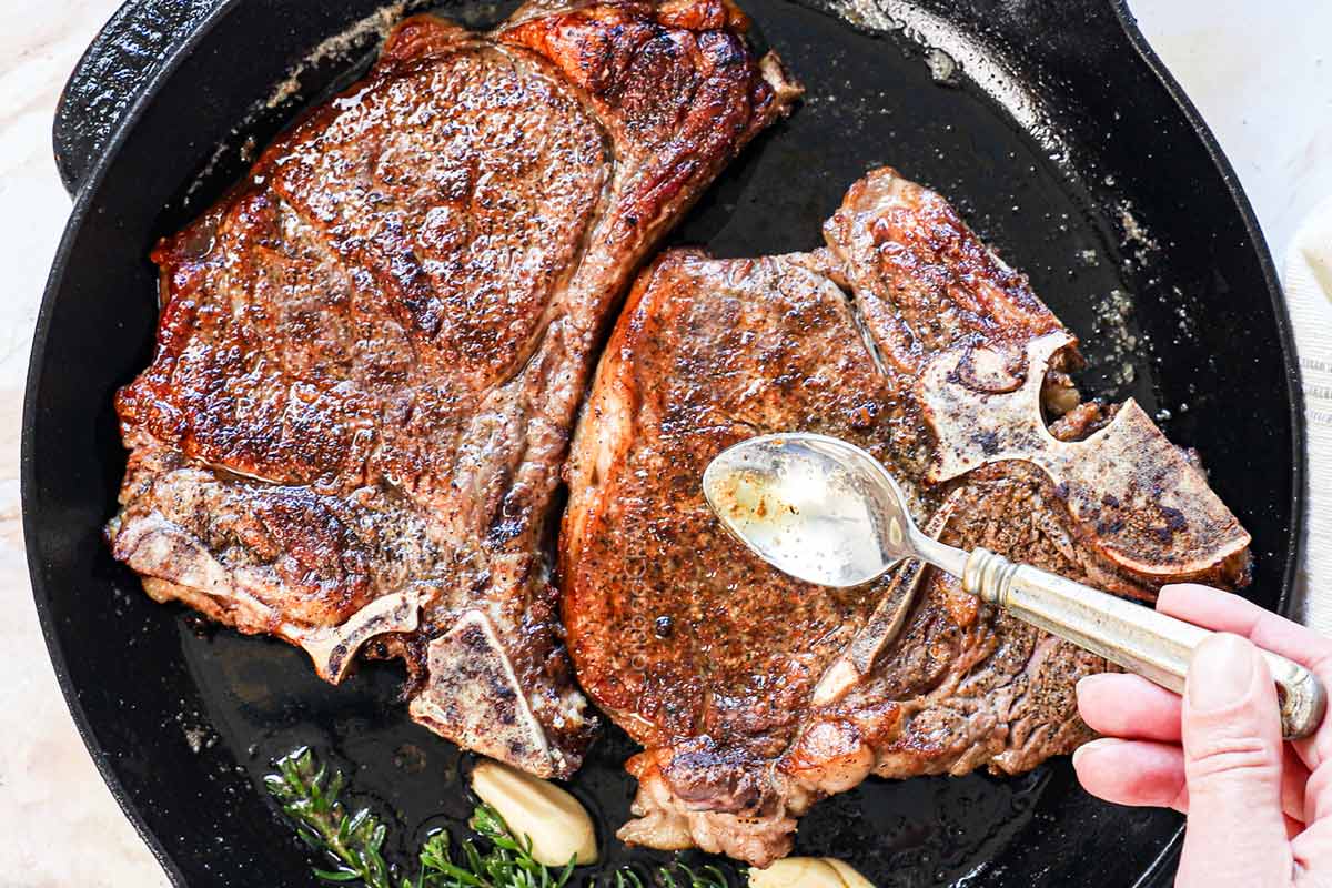 showing how to reverse sear steak by pan searing, then basting with butter