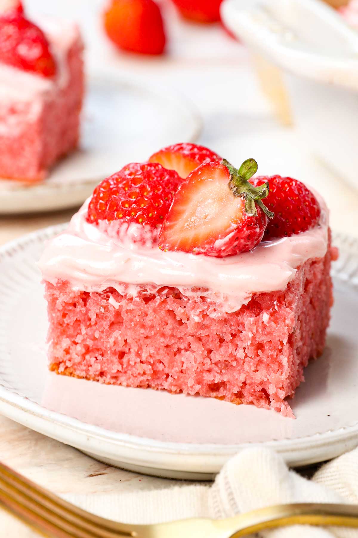 a slice of easy strawberry cake on a plate showing how fluffy and moist it is