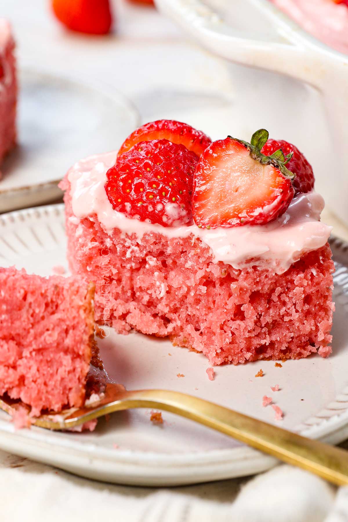 strawberry sheet cake with a bite taken out showing the inside of the fluffy cake