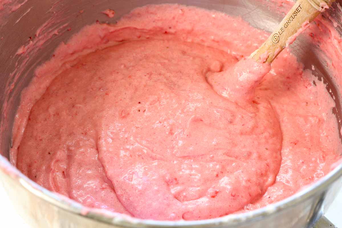 showing how to make strawberry cake by mixing the pureed strawberries into the batter with a spatula