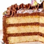 up close of yellow cake recipe with three tiers of cake frosted with chocolate frosting