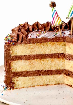 up close of yellow cake recipe with three tiers of cake frosted with chocolate frosting