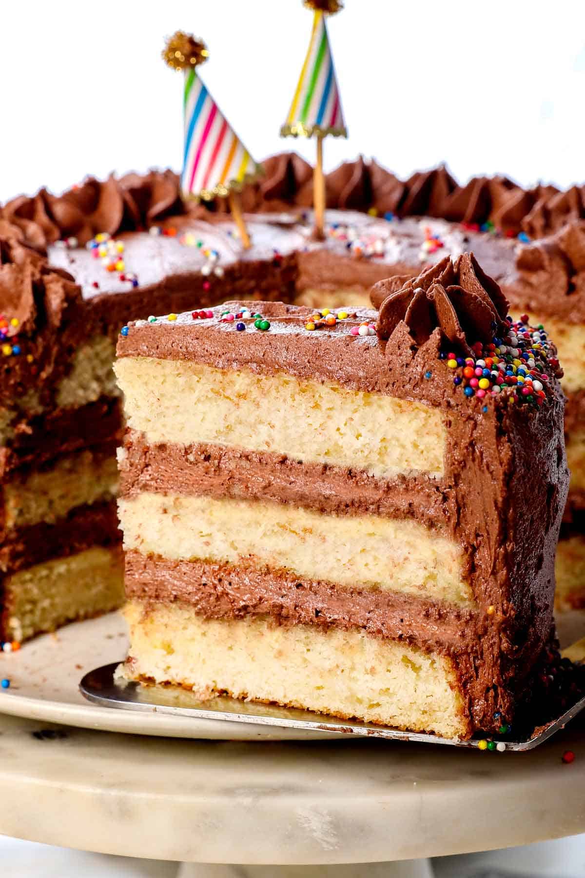 best yellow cake recipe on a pedestal showing the fluffy layers and rich chocolate frosting