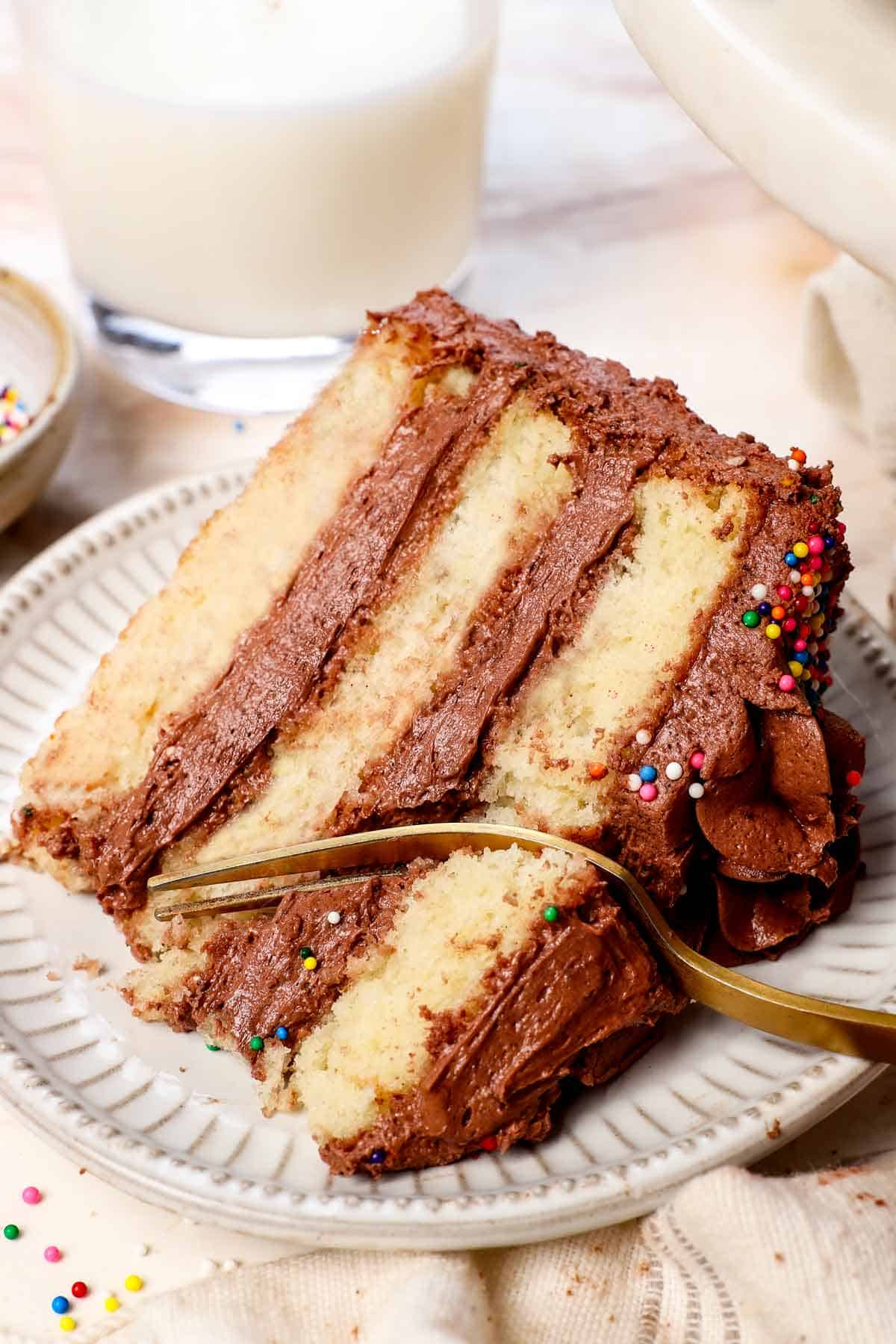 a slice of homemade yellow cake on a plate with a fork taking a bite showing how moist and tender it is