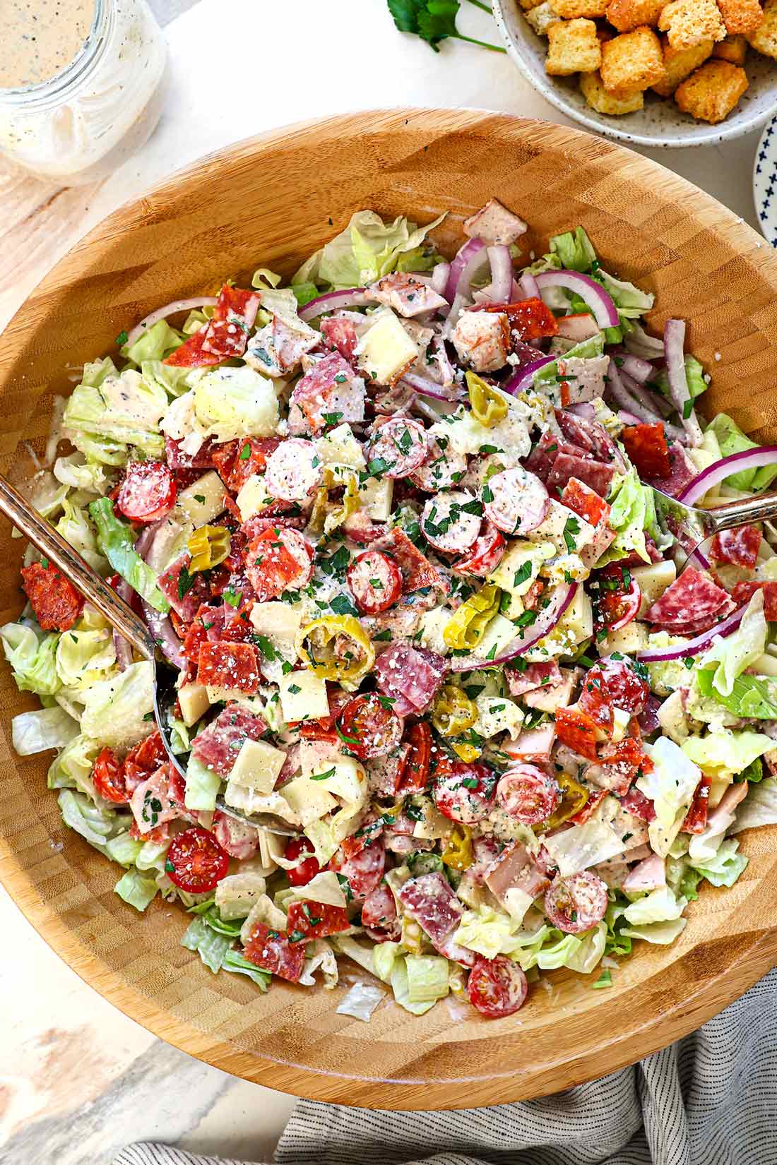 showing how to make Grinder salad by tossing the salad ingredients with the dressing