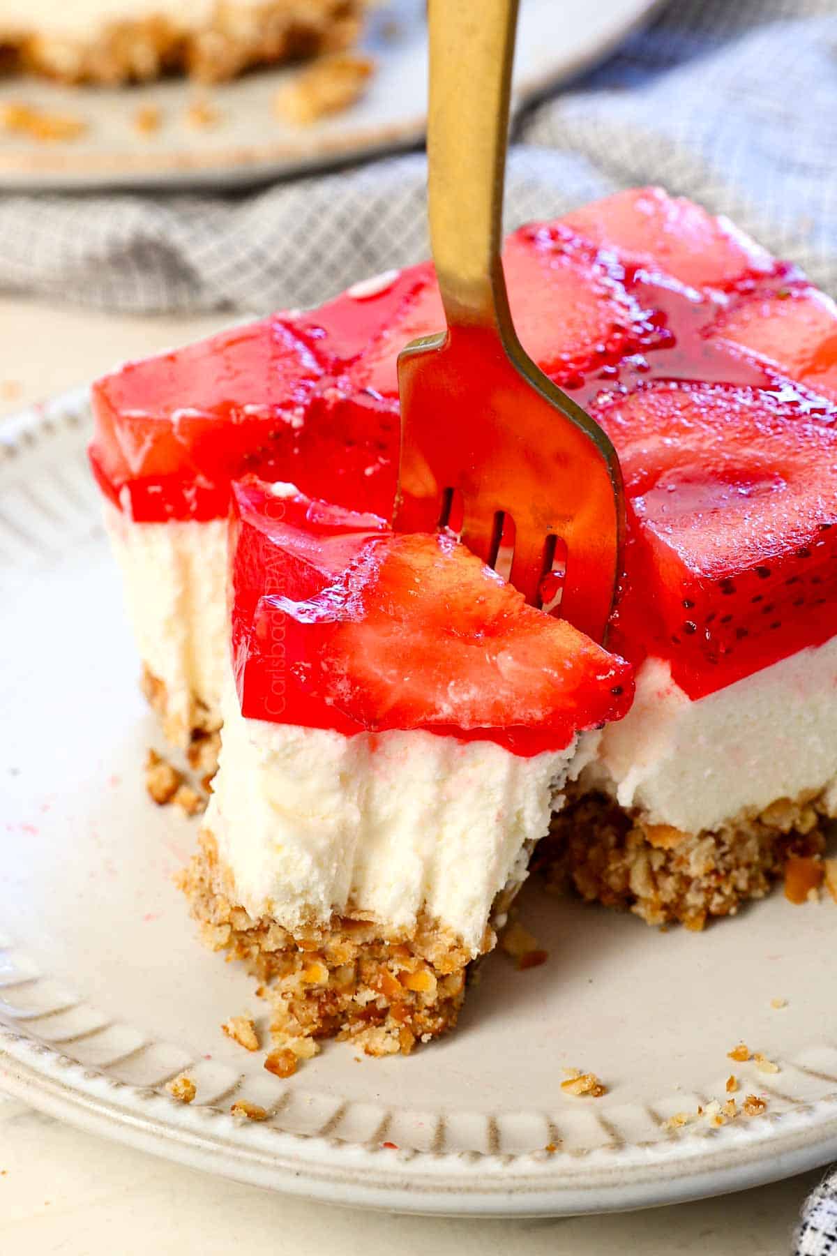 a fork taking a bite out of strawberry pretzel salad showing how creamy it is