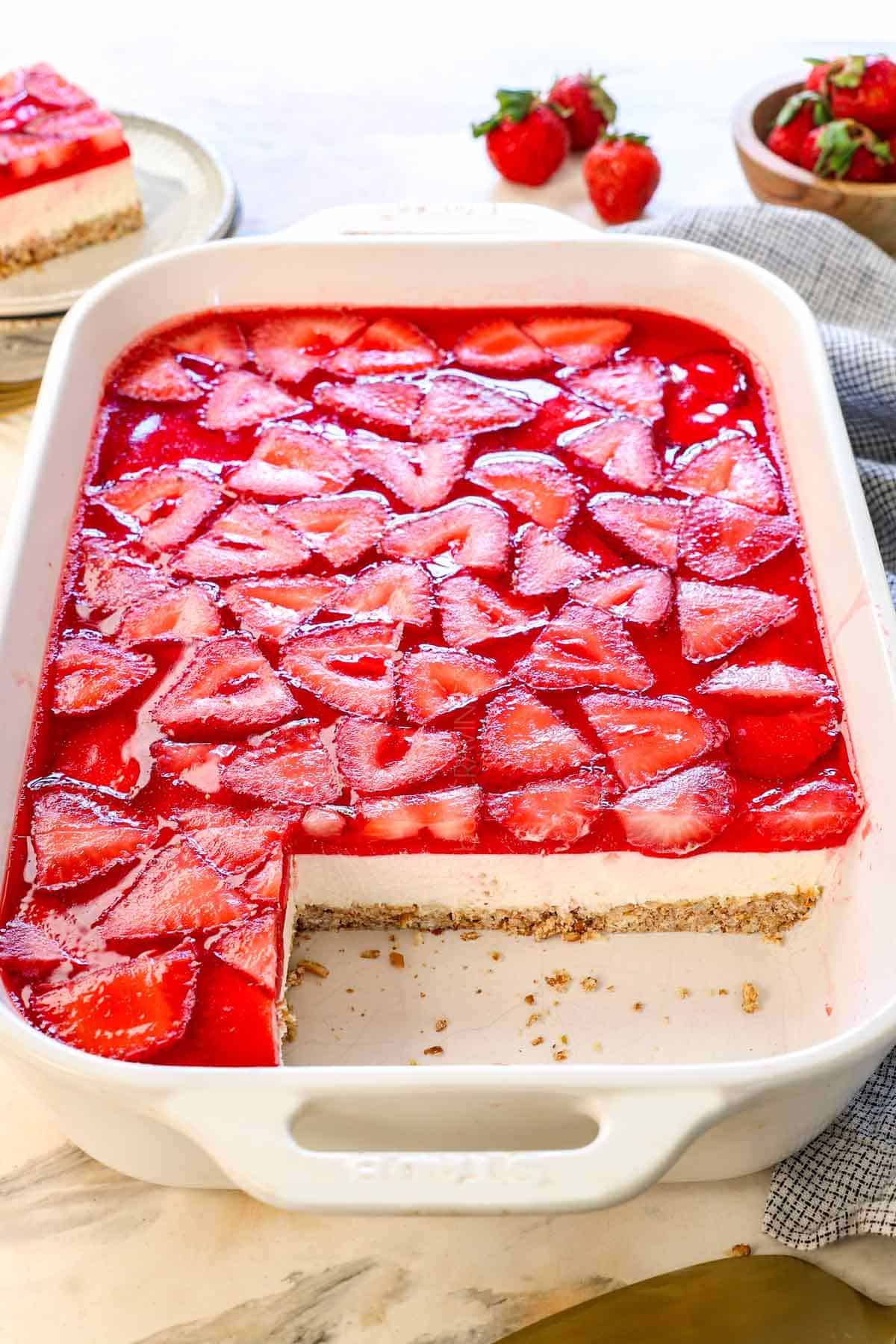 recipe for pretzel salad strawberry with slices removed showing the layers of pretzels, cream cheese filling and strawberries in jell-o