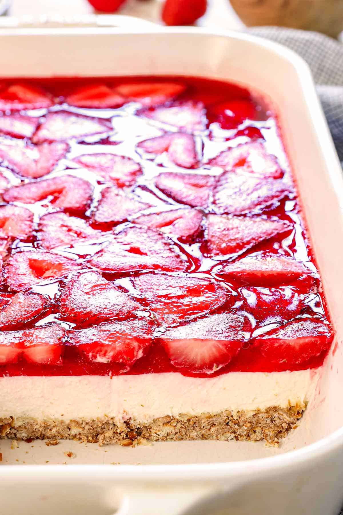 up close of strawberry pretzel salad reciope with slices removed showing the layers of pretzels, cream cheese filling and strawberries in jell-o