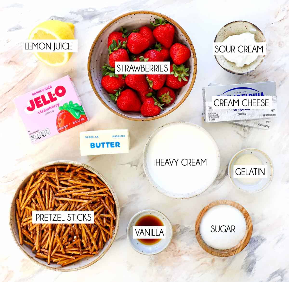 top view of Strawberry Pretzel Salad ingredients: strawberries, strawberry Jell-o, pretzel sticks, cream cheese, heavy cream, sugar, gelatin, sour cream, lemon juice, butter