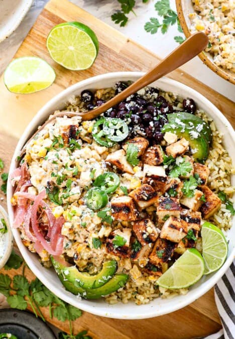 top view of street corn chicken rice bowl with Mexican street corn, Mexican chicken, cilantro lime rice, black beans, pickled red onions, cilantro, cotija and jalapeno