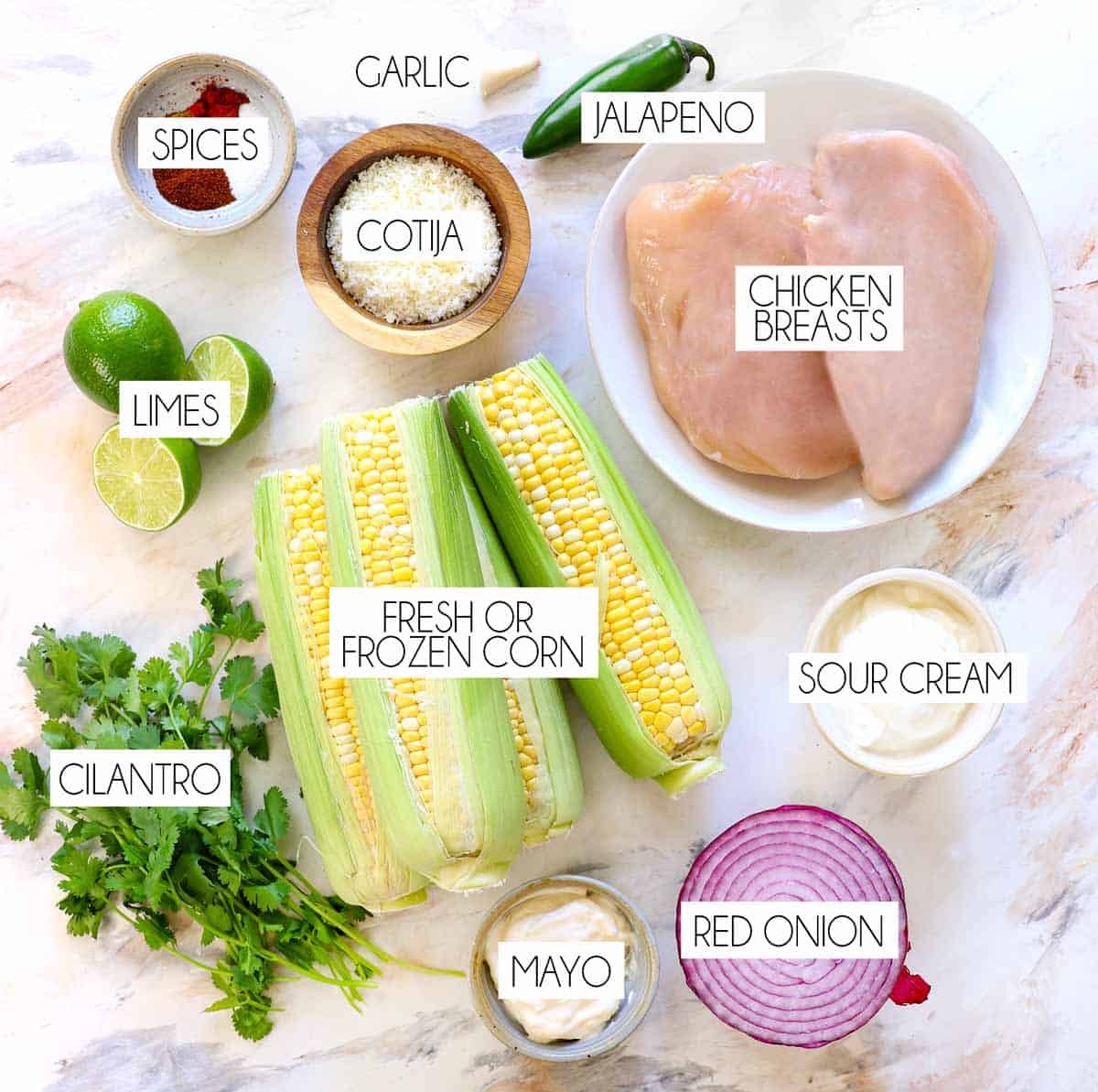 top view of street corn chicken rice bowl ingredients: fresh corn, chicken breasts, mayonnaise, sour cream, Cotija cheese, lime juice, cilantro, red onion, jalapeno, and spices