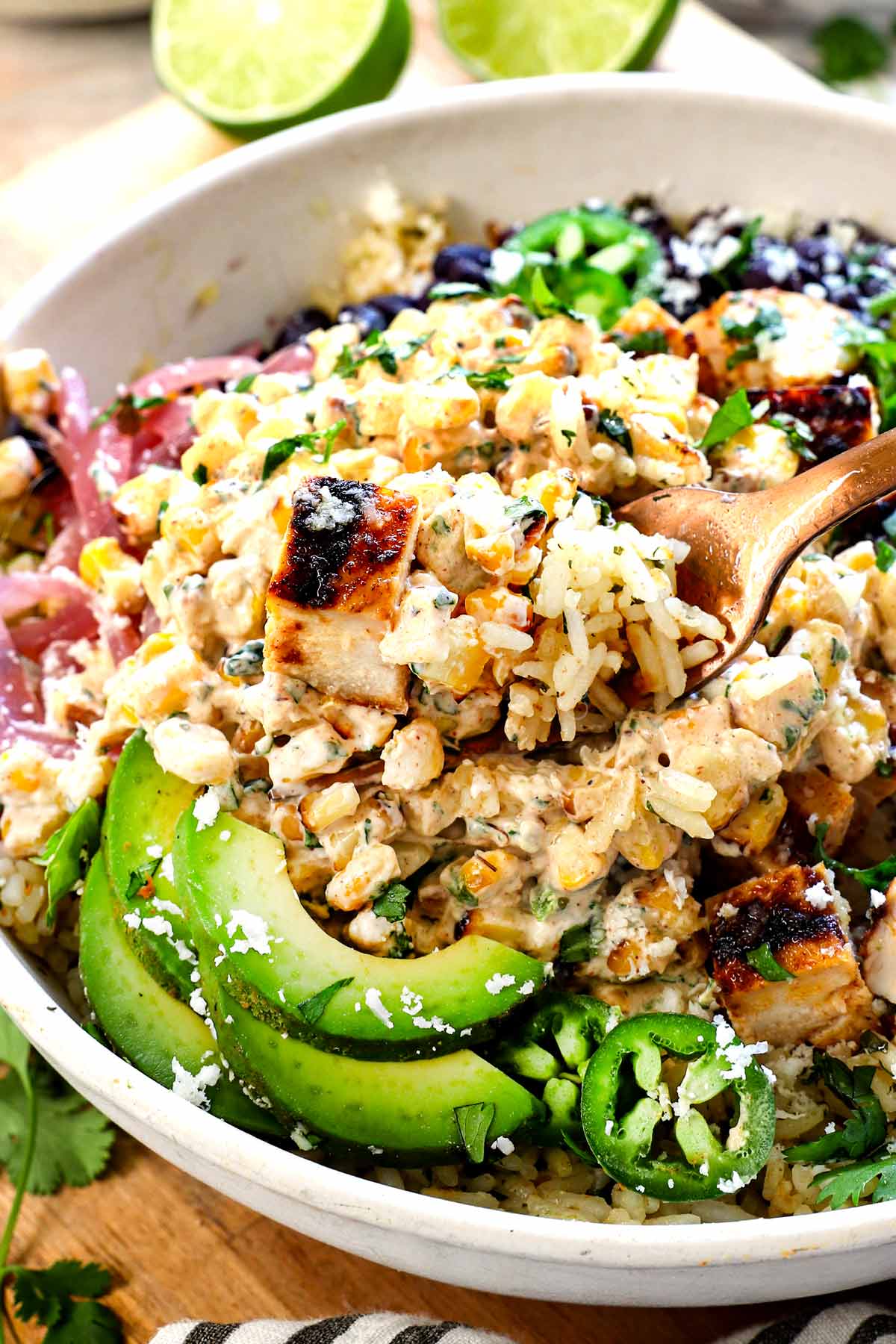 street corn chicken bowl with a fork taking a bite of the chicken, rice, and street corn