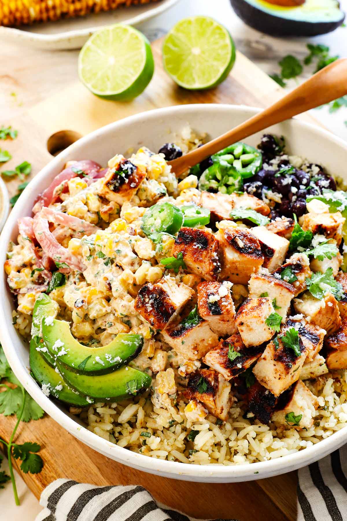 street corn rice bowl recipe topped with avocados, black beans, red onions, jalapenos, cilantro and cotija