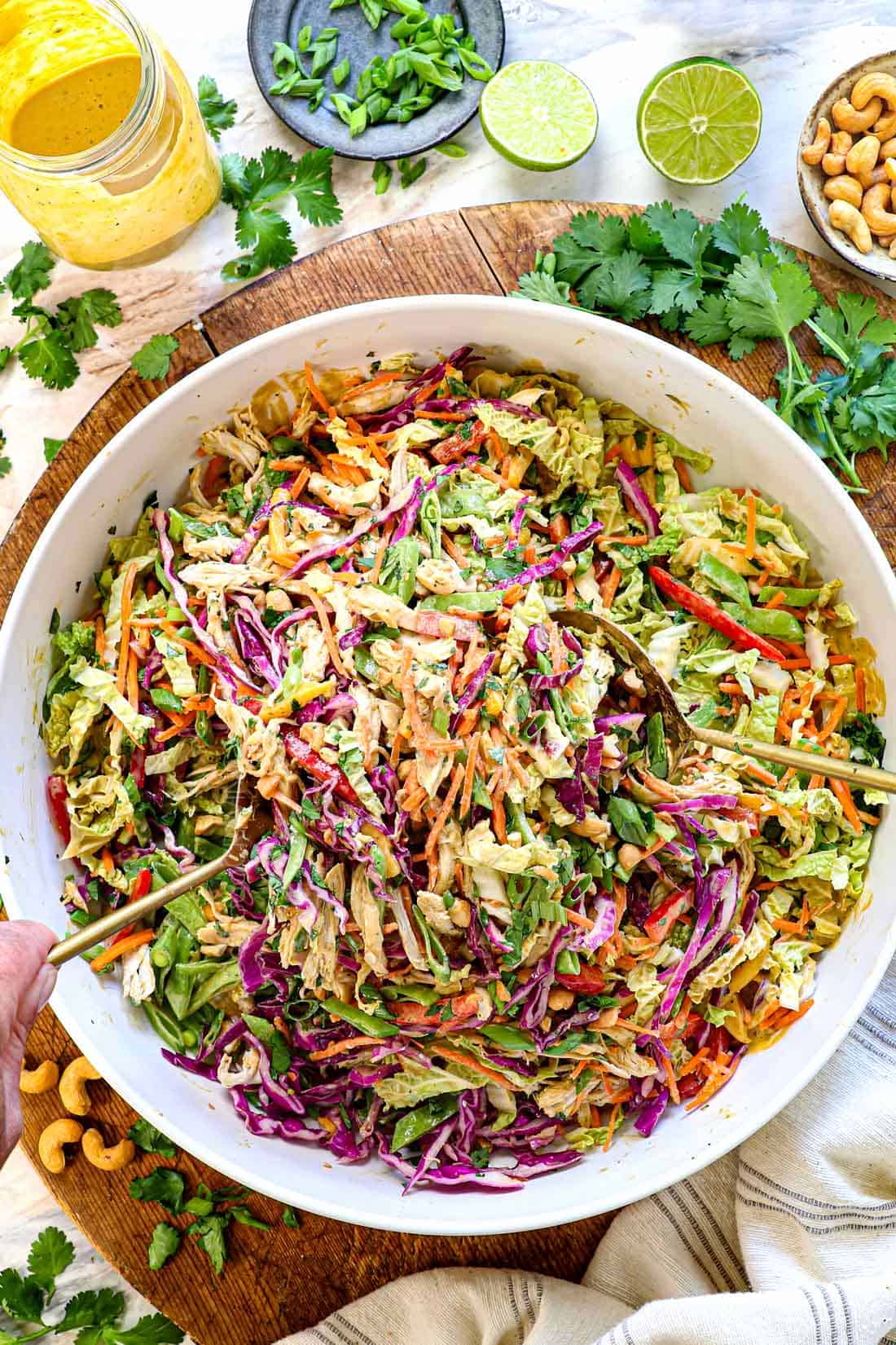 showing how to make Thai chicken salad recipe by tossing the salad with the dressing