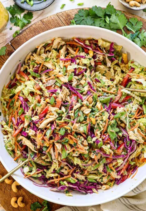 showing how to make Thai chicken salad recipe by tossing the salad with the dressing