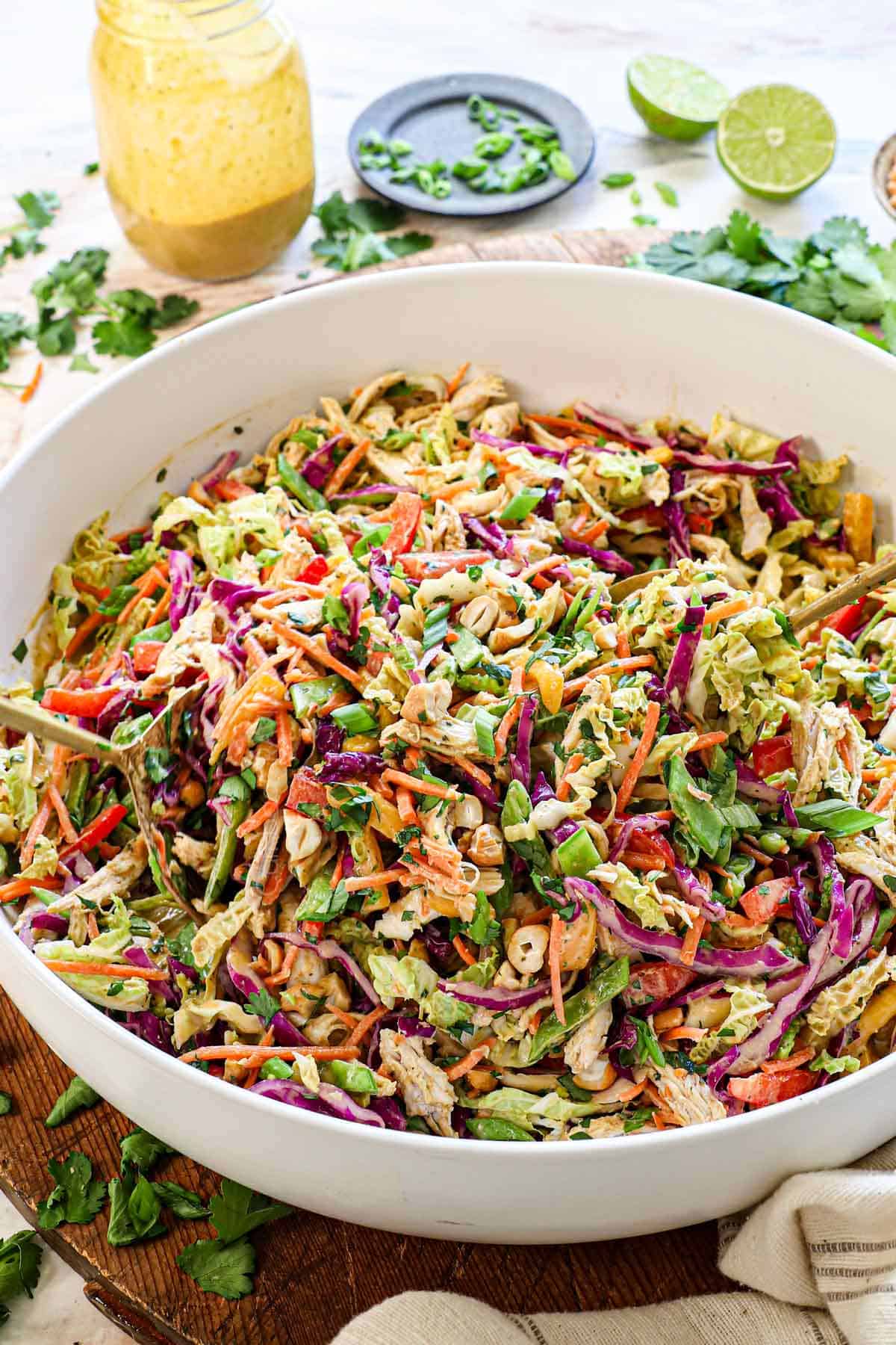 showing how to make Thai chicken salad recipe by tossing the salad with the dressing