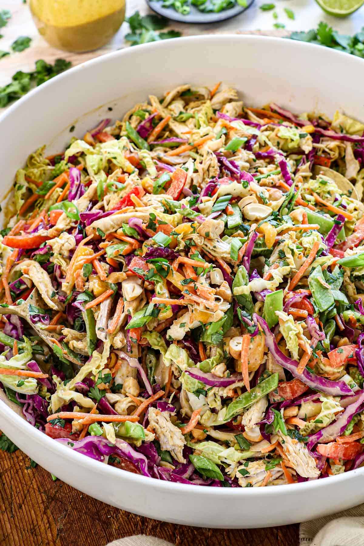 showing how to make Thai chicken salad recipe by tossing the salad with the dressing