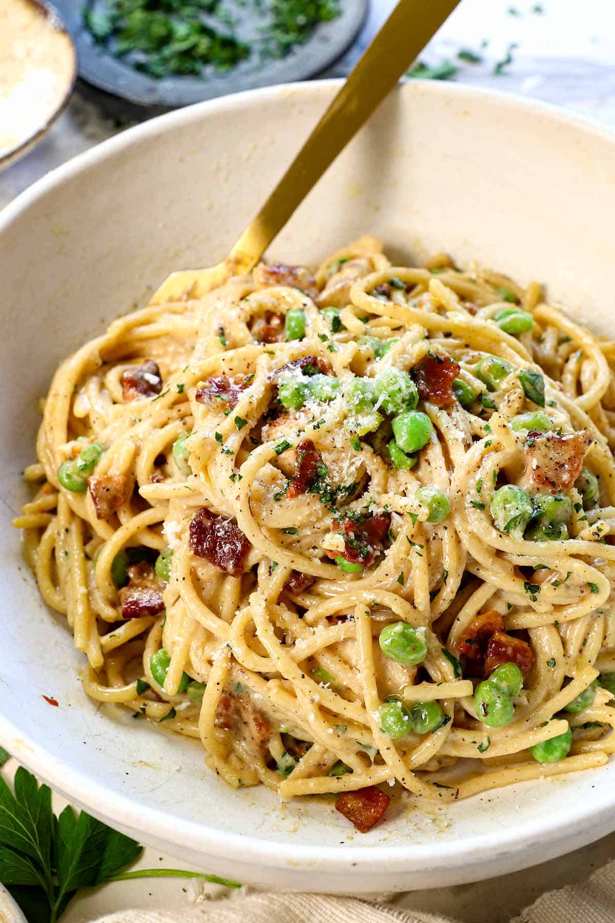 showing how to make chicken carbonara recipe by serving in a bowl garnished with Pecorino Romano and parsley