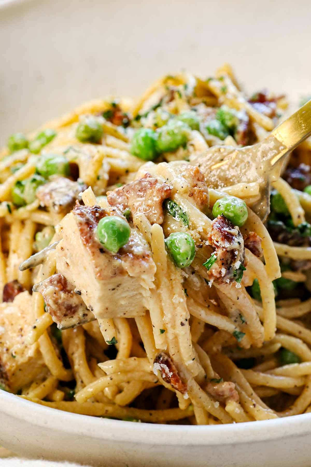 up close of a bite of chicken pasta carbonara with creamy spaghetti, peas, chicken, and bacon
