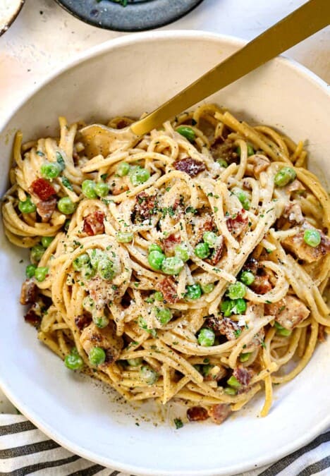 top view of chicken carbonara recipe in a bowl with a fork twirling the creamy pasta