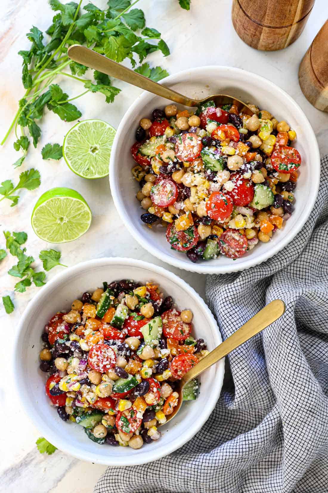 two bowls of dense bean salad being served garnished with cotija and cilantro