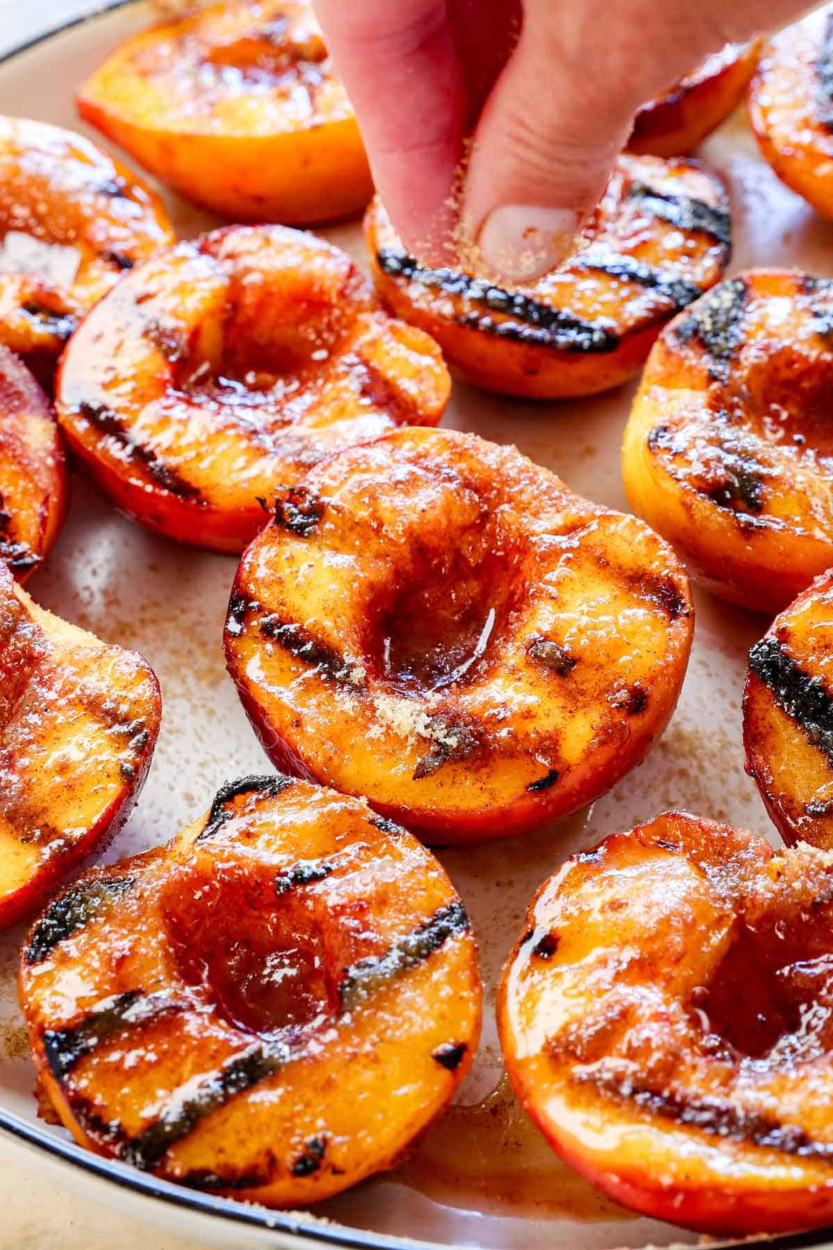showing how to grill peaches by sprinkling with brown sugar after they are grilled