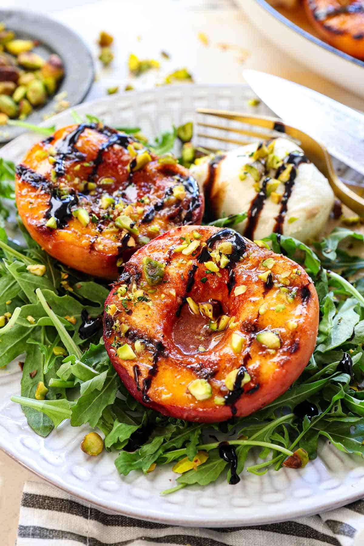 up close of grilled peaches and burrata salad drizzled with balsamic glaze