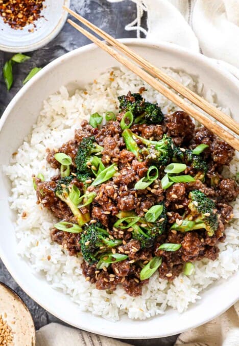top view of ground beef and broccoli being served over white rice garnished by green onions