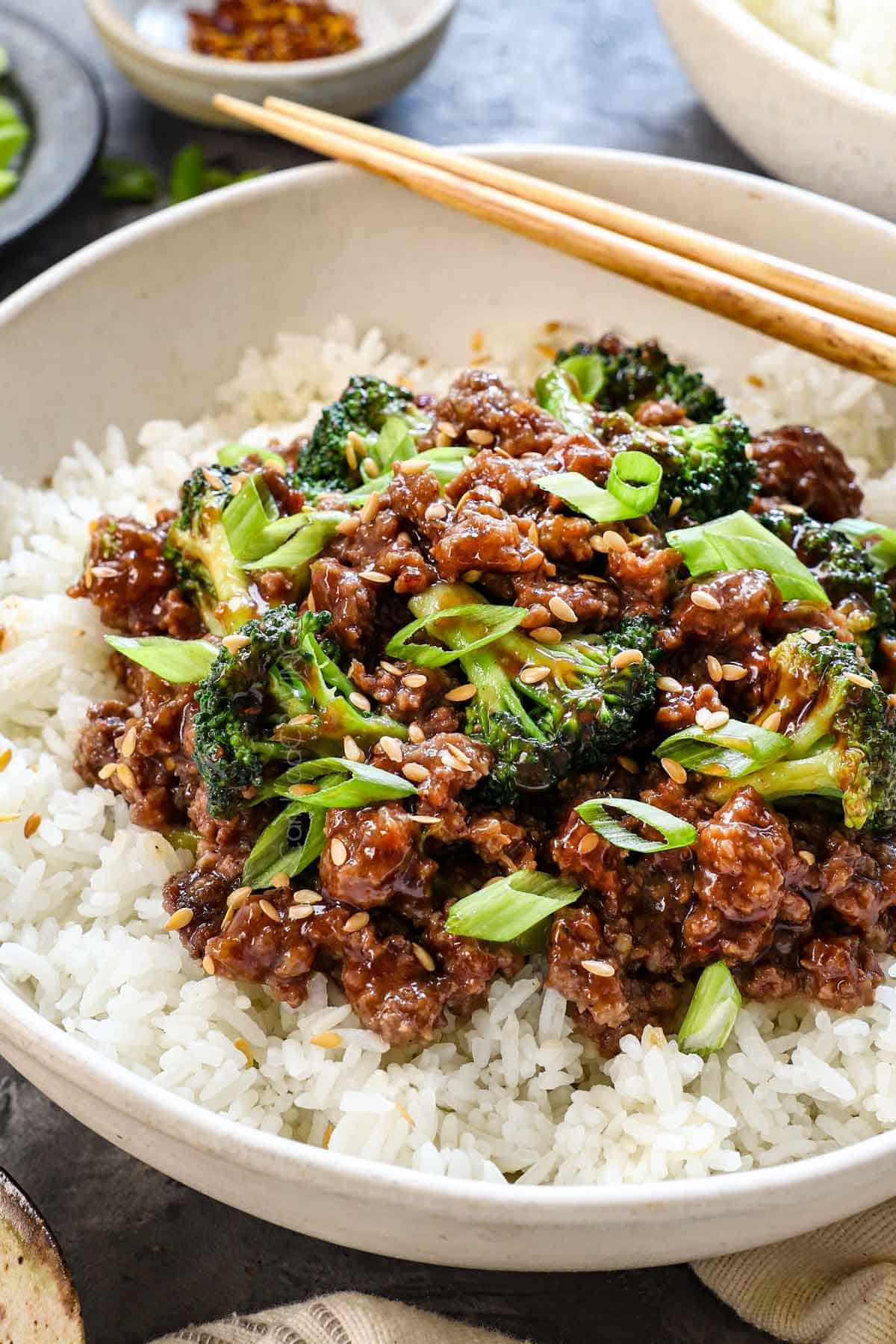 showing how to serve ground beef and broccoli in a bowl of rice garnished with sesame seeds and green onions