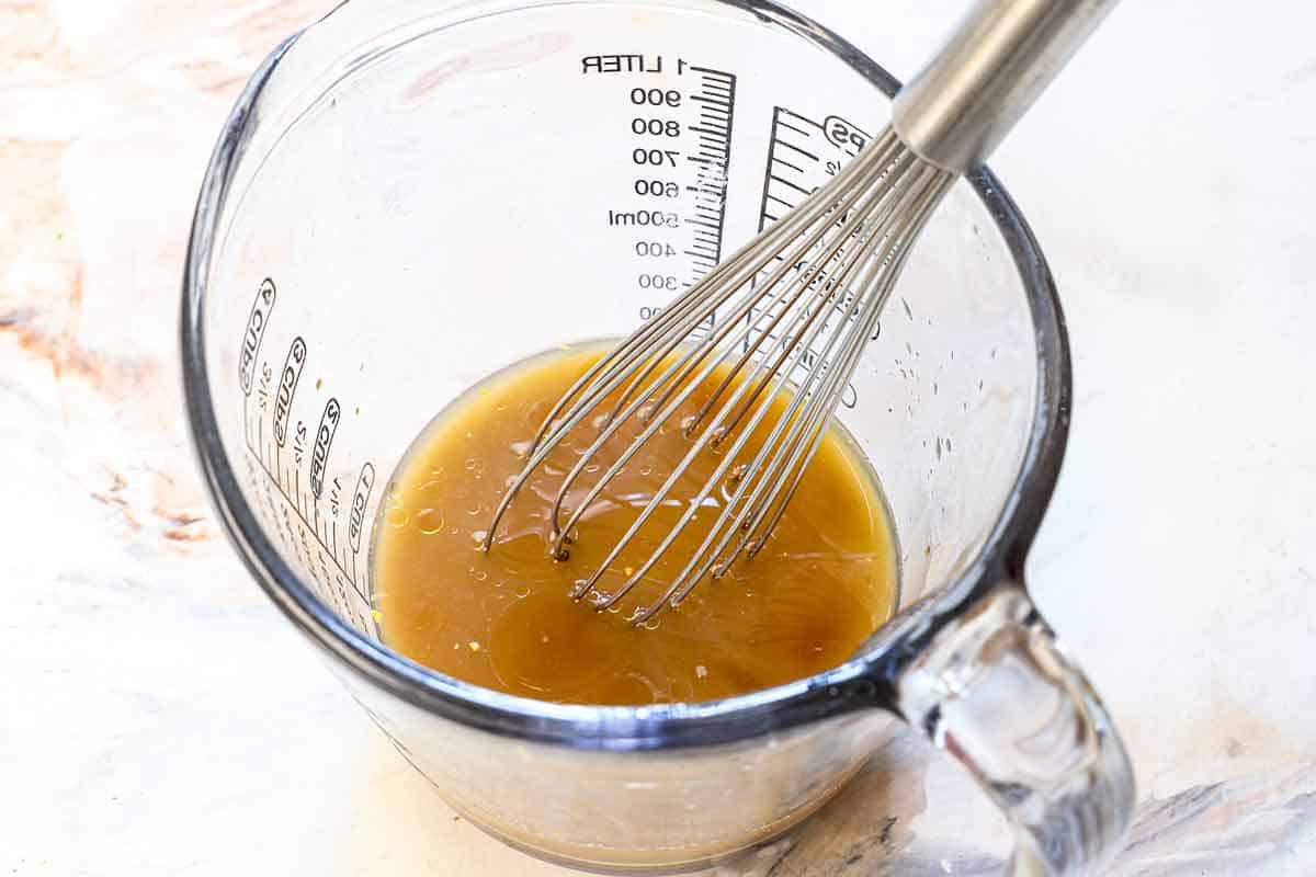 showing how to make ground beef and broccoli recipe by whisking the sauce ingredients together in a liquid measuring cup