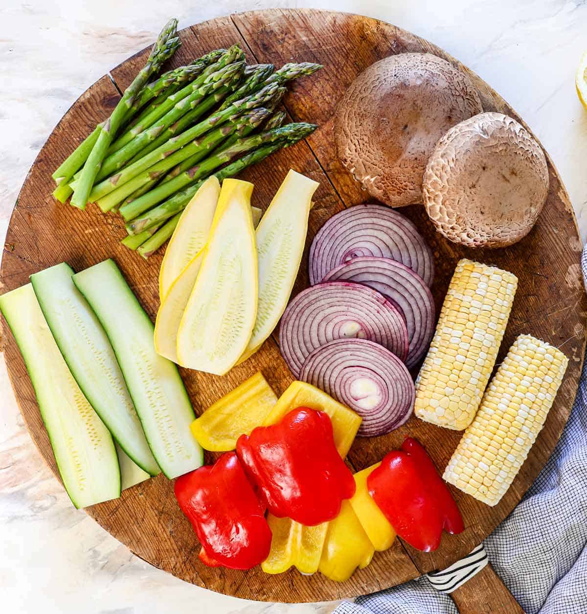 Showing how to cut vegetables for grilled vegetables by slicing/chopping them and adding them to a large cutting board to see the sizes