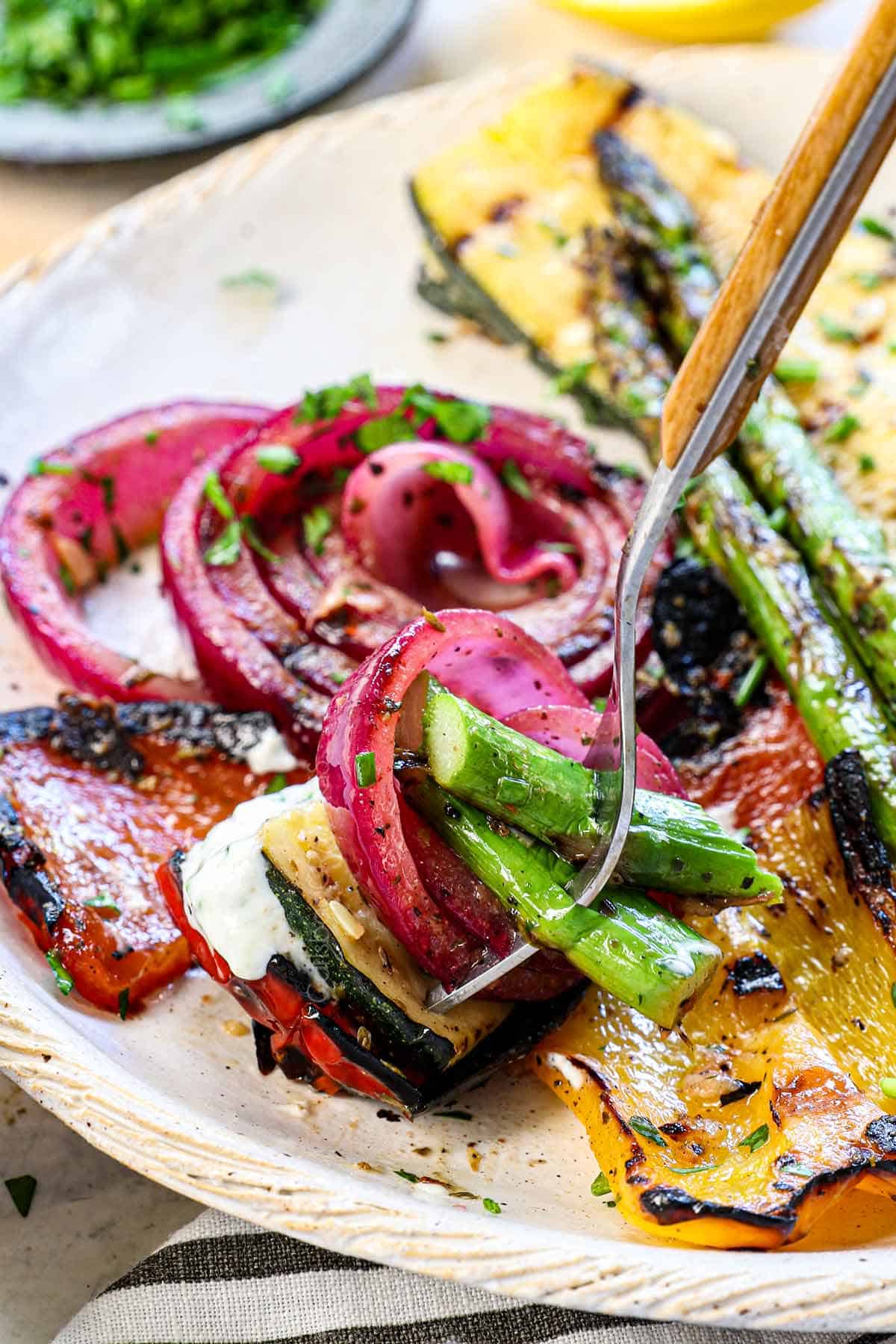 up close of grilled vegetables recipe on a fork being served with yogurt sauce