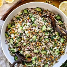 Top view of Jennifer Aniston Salad in a bowl with chicken, quinoa, chickpeas, cucumbers, pistachios, feta, mint, and basil