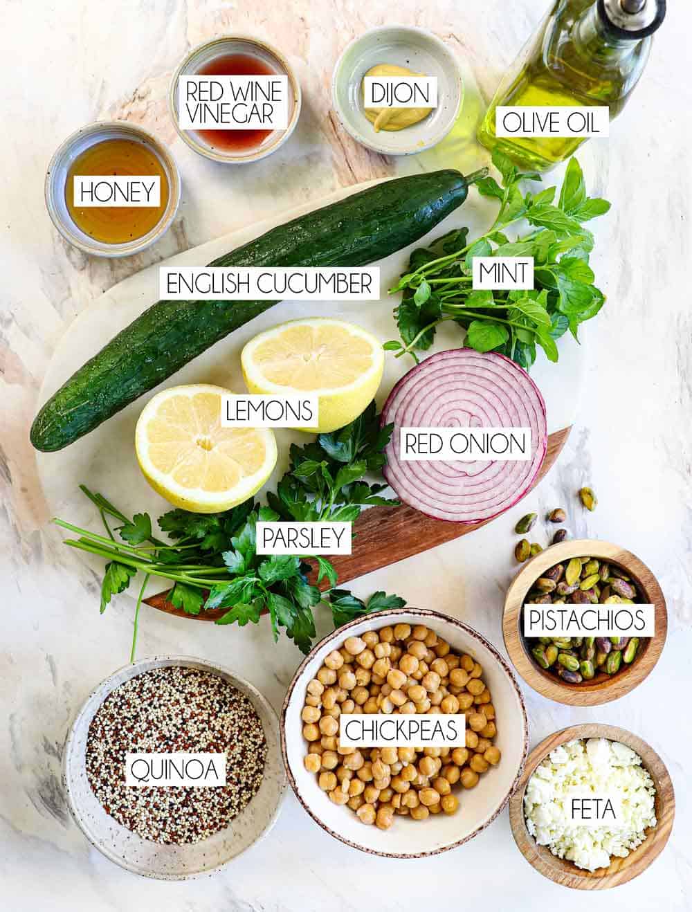 Top view of Jennifer Salad Aniston ingredients: quinoa, chickpeas, pistachios, feta, red onion, English cucumber, mint, parsley, lemon juice, olive oil, Dijon, honey