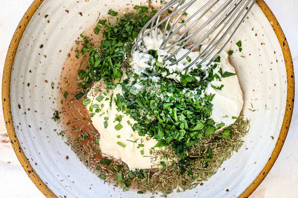 showing how to make waldorf salad by whisking the dressing ingredients together of mayonnaise, yogurt, sugar, red wine vinegar, parsley, dill