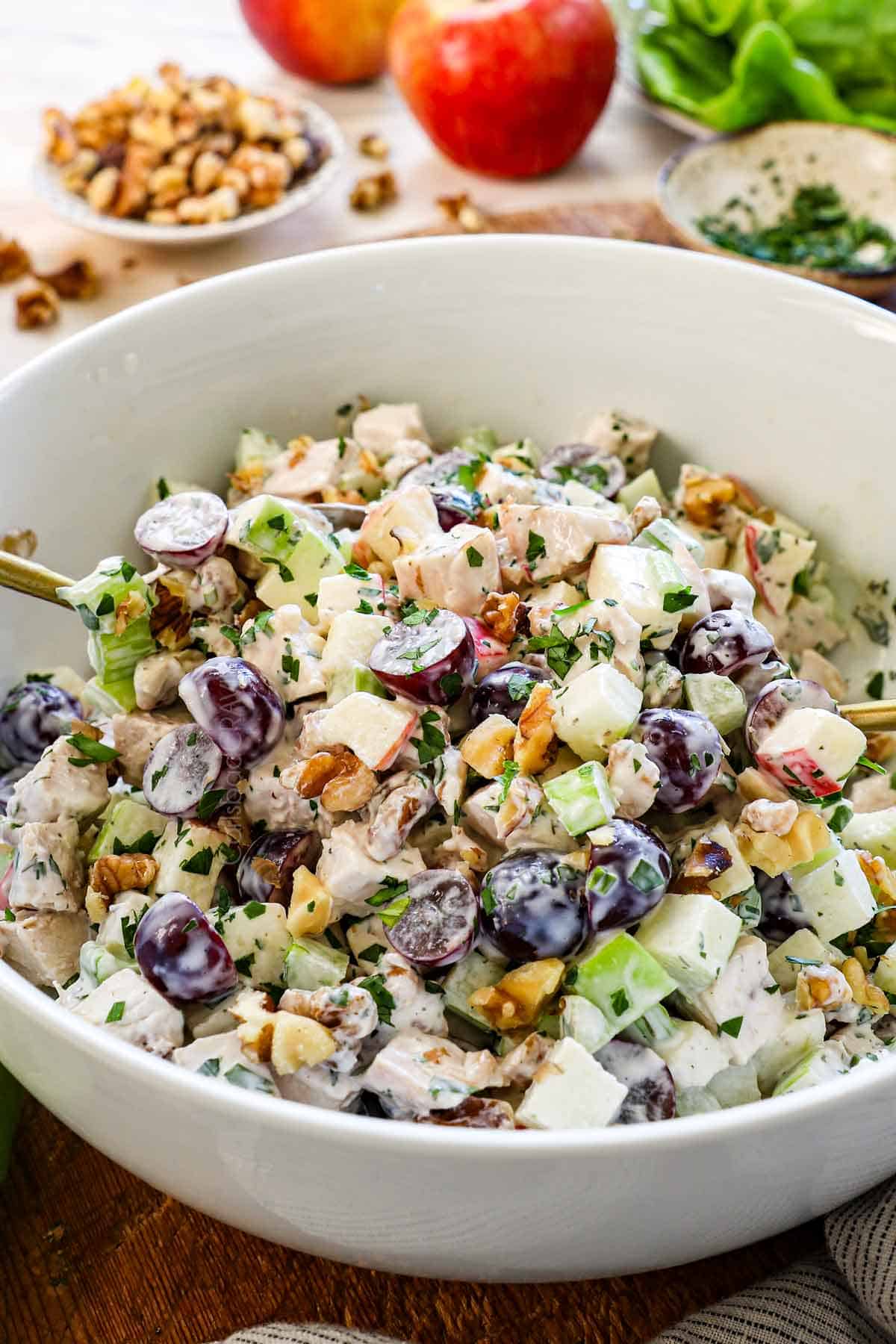 showing how to make waldorf salad by tossing it with the dressing