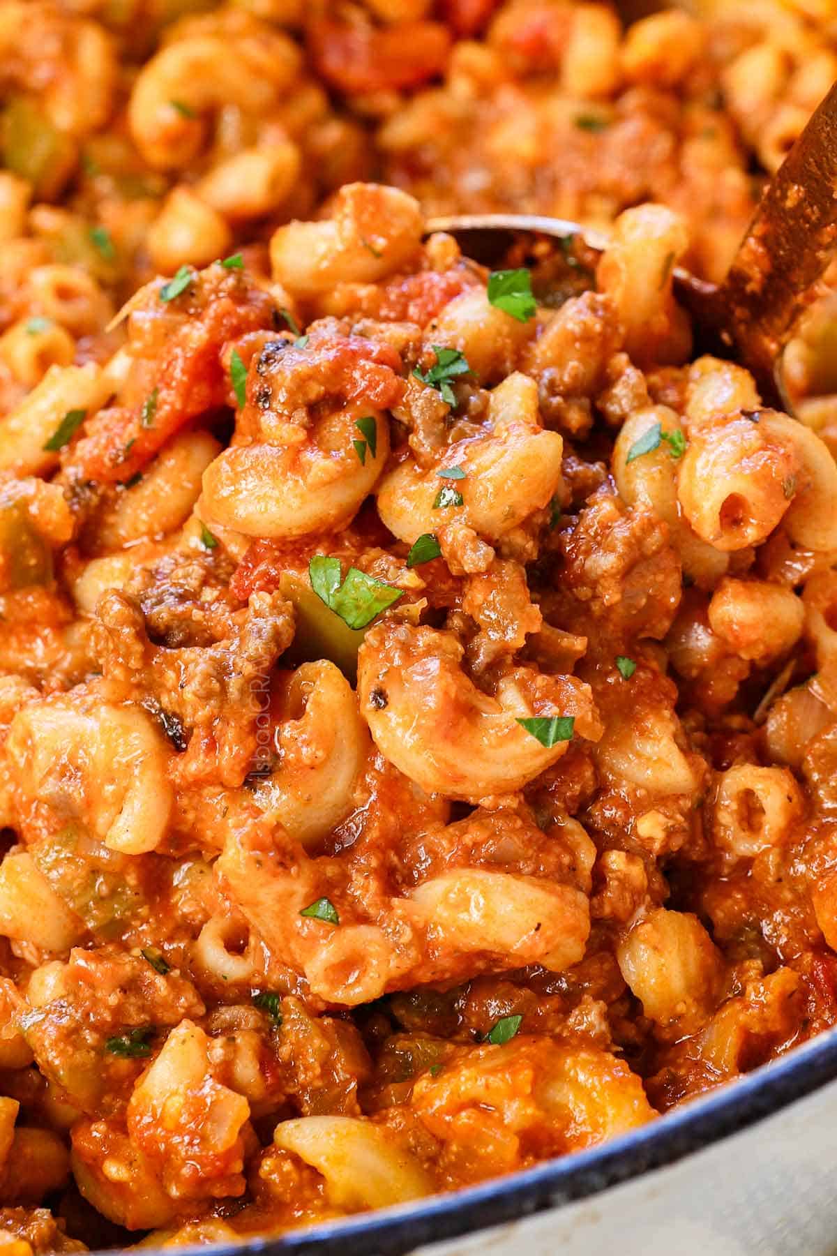 up close of scooping American chop suey showing the beef, veggies and pasta and how saucy it is