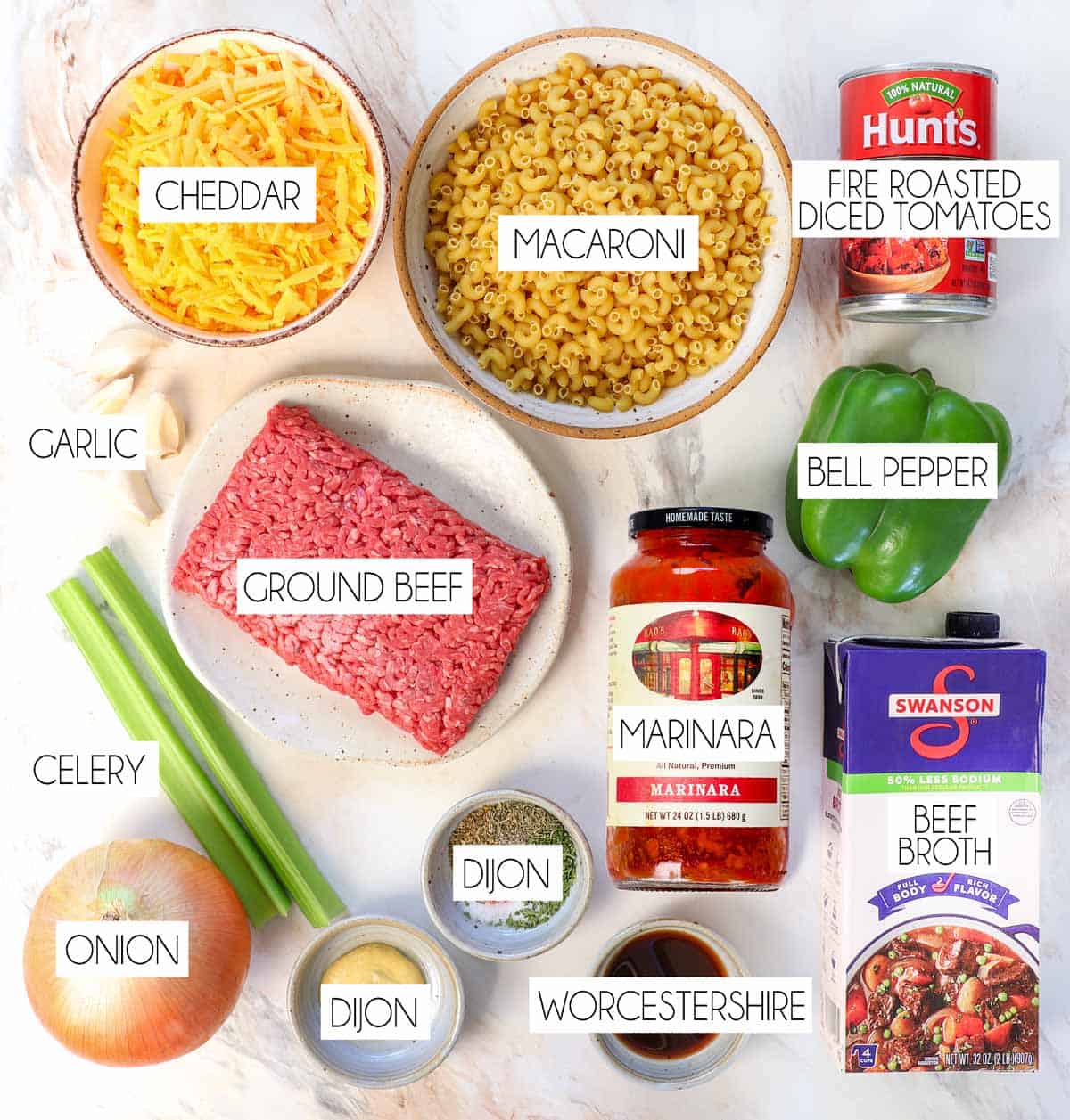 top view of American Chop Suey ingredients - macaroni, ground beef, diced tomatoes, marinara, beef broth, green bell pepper, celery, onion, Dijon, Worcestershire, spices