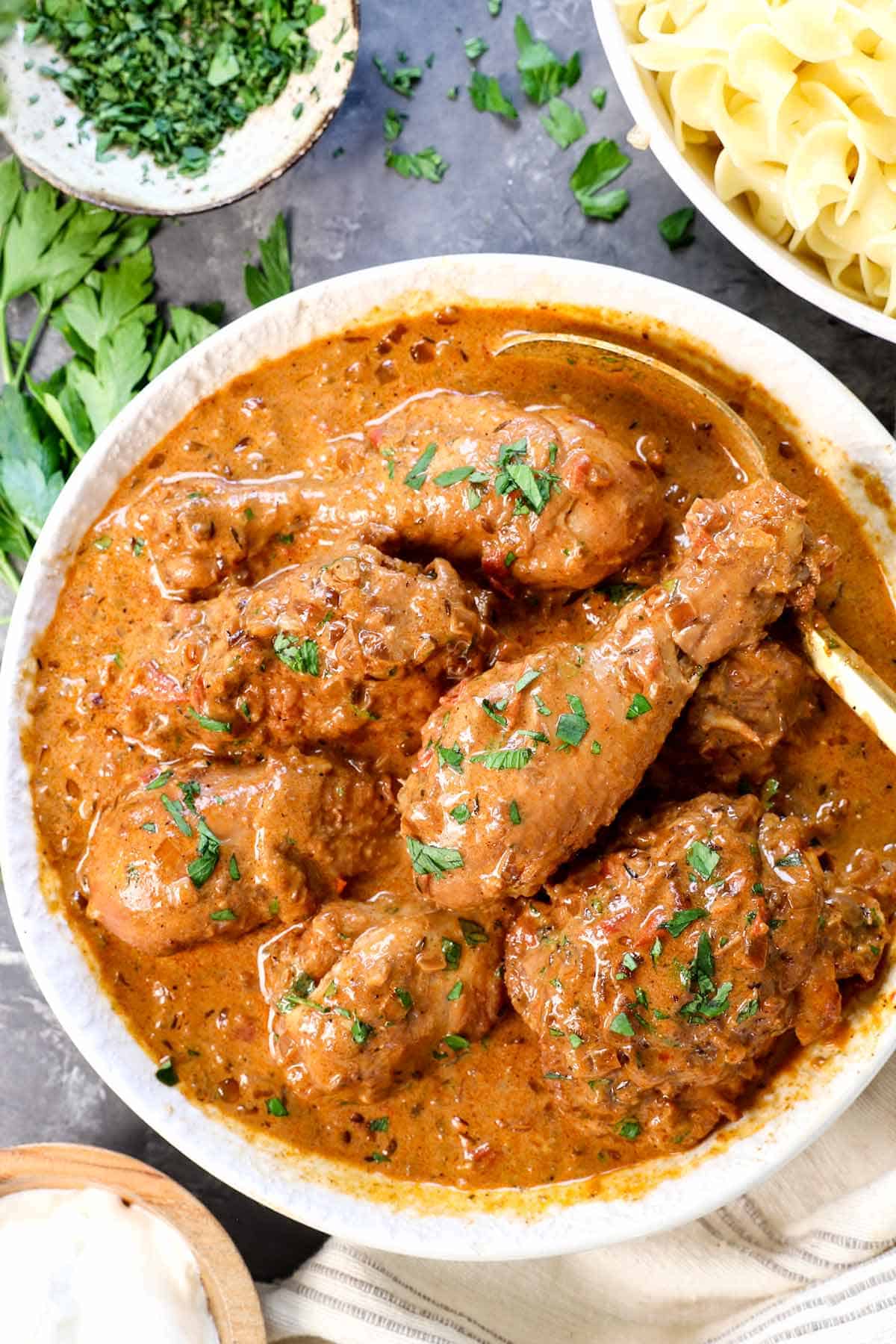 showing how to serve chicken paprikash in a bowl garnished with parsley