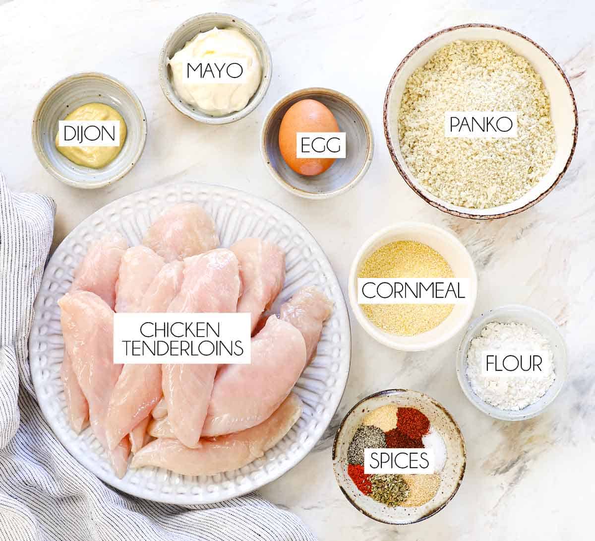 Top view of chicken strips ingredients: chicken tenderloins, panko, flour, egg, mayonnaise, cornmeal, Dijon, spices