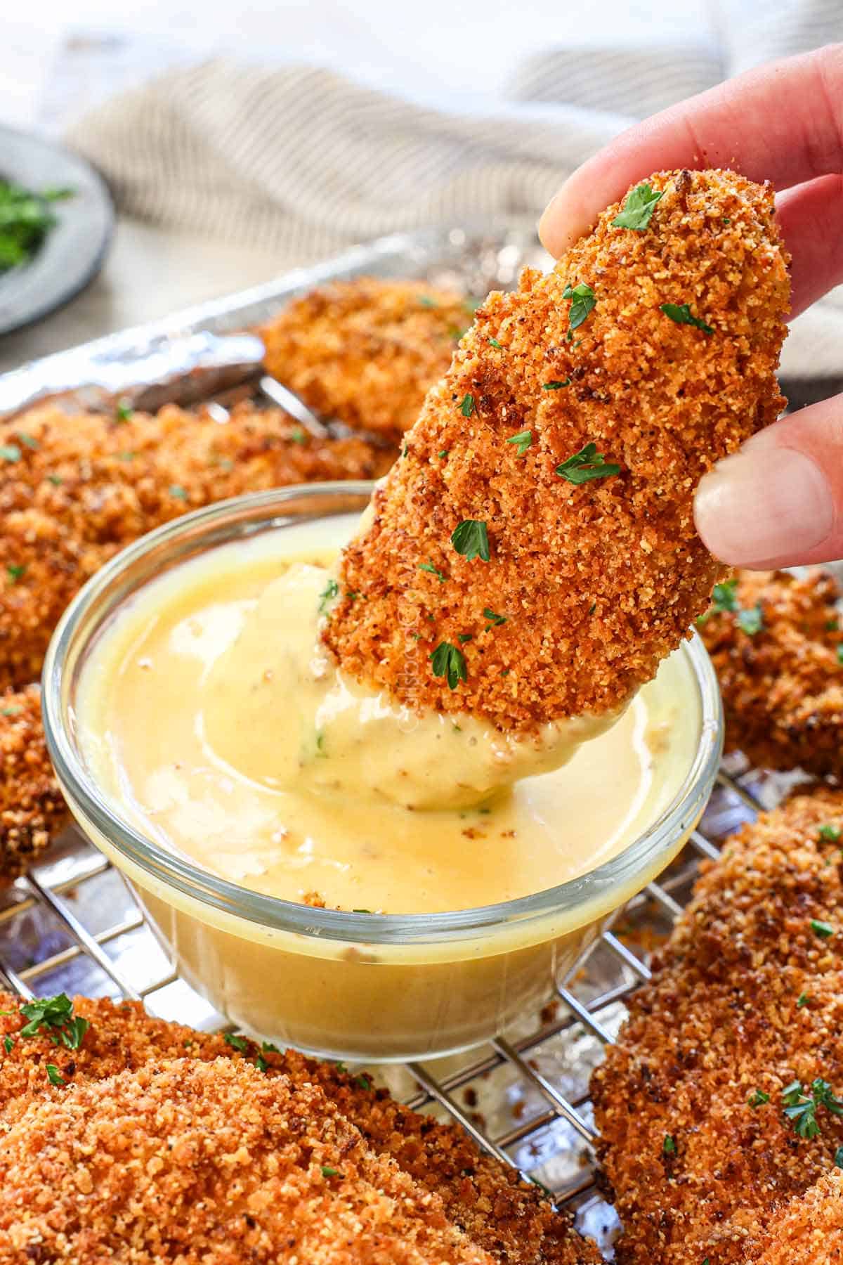 chicken strips being dipped in honey mustard sauce