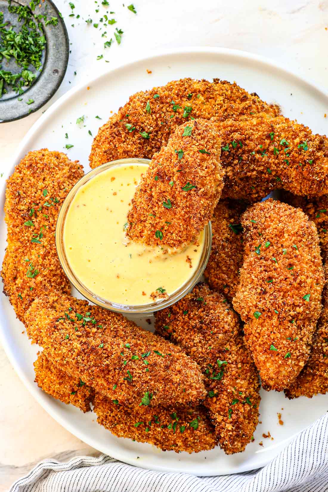 chicken tenders breaded in panko on a platter garnished with parsley