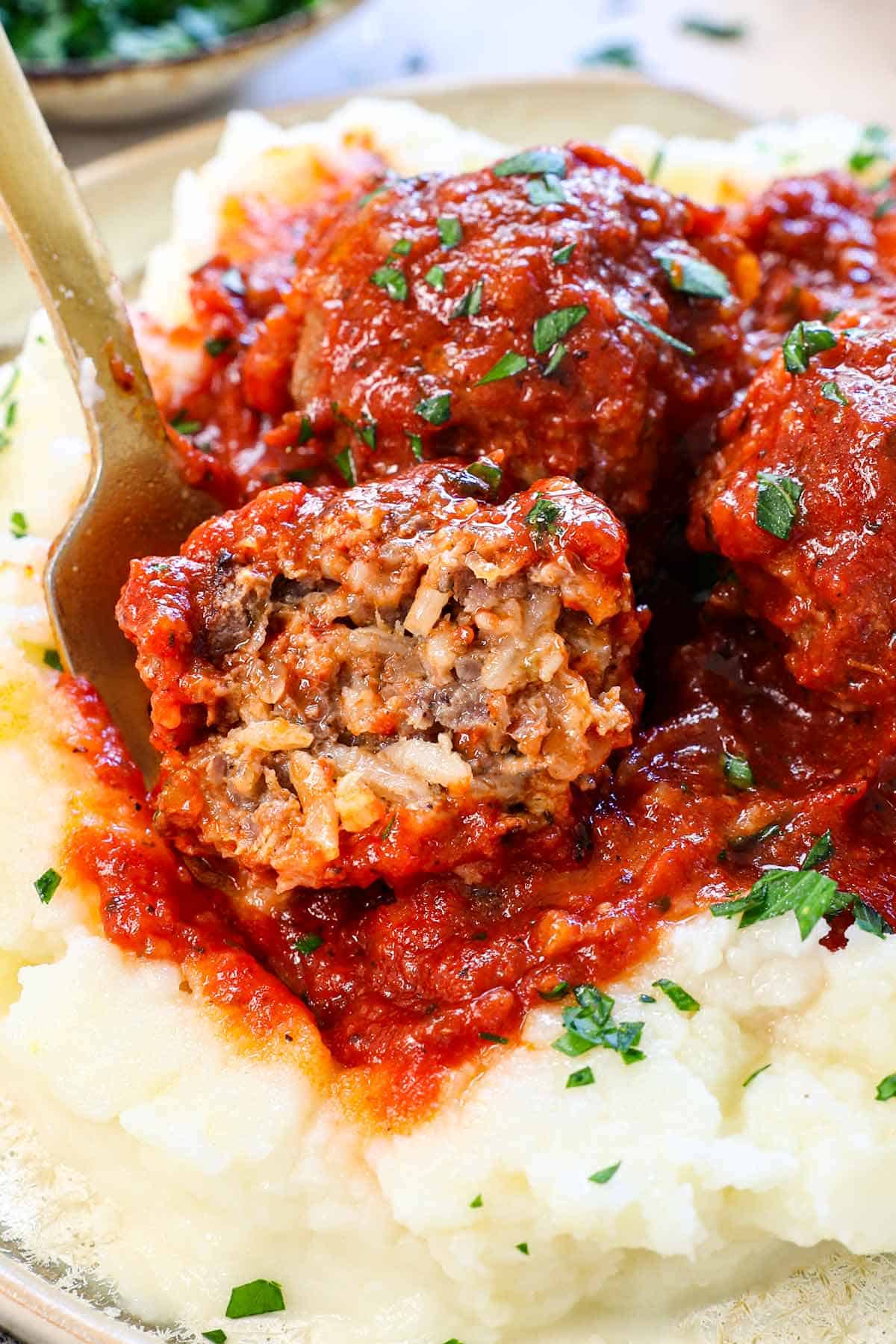 up close of porcupine meatballs with a bite taken out of a meatballs showing the cooked rice inside juicy meat
