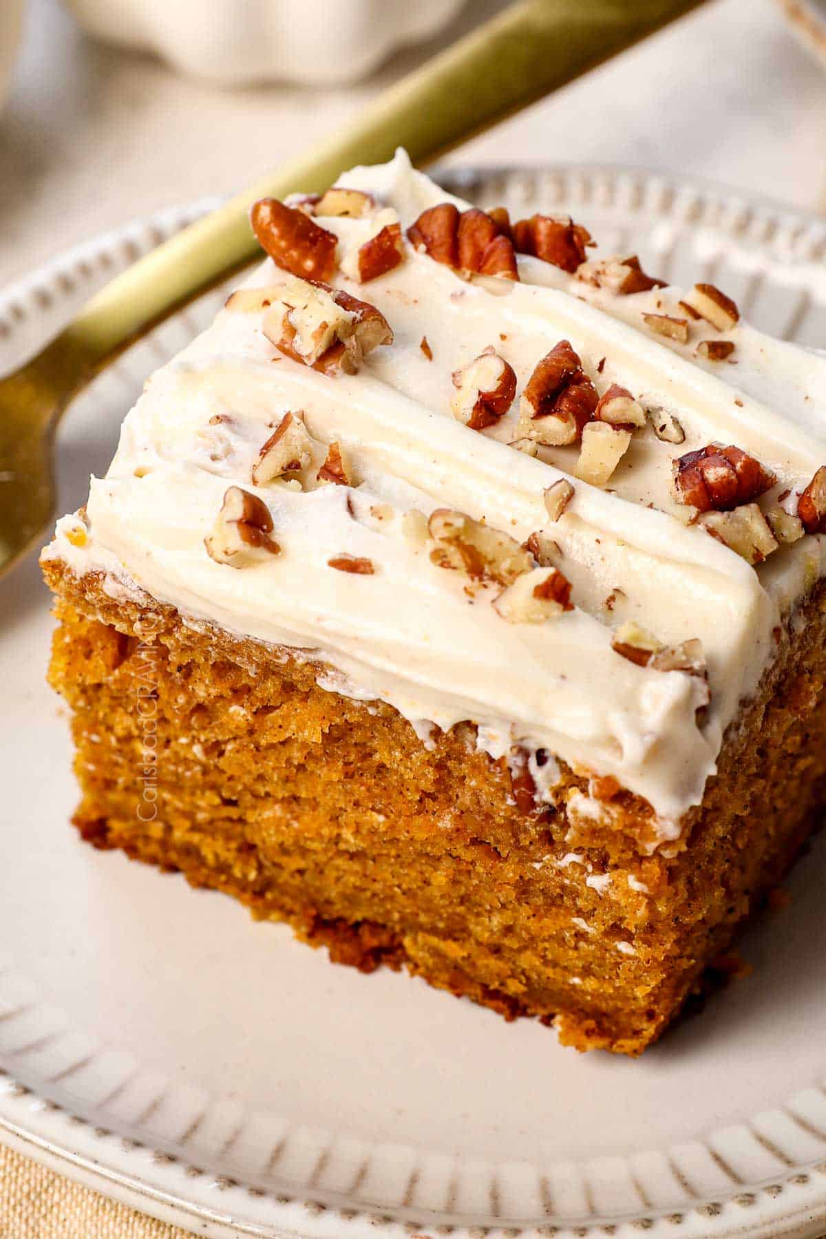 a slice of pumpkin cake recipe with cream cheese frosting on a plate showing how moist it is